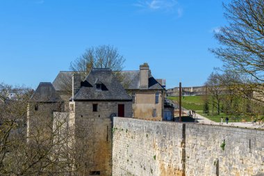 Caen, Fransa - 31 Mart 2025. Caen Kalesi 'nin antik taş duvarları yukarı çıkan bir merdivenle yükseldi. Yakınlardaki modern yapılar ise bölgenin uzun evrimini ön plana çıkardılar.