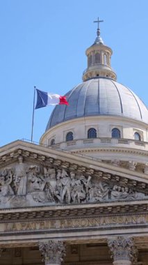 Paris 'teki Pantheon mimarisinin ayrıntılı heykelleri ve kubbenin üstünde Fransız bayrağı var. Seyahat, kültür, tarih ve Avrupa turizm kavramları için ideal ikonik manzara