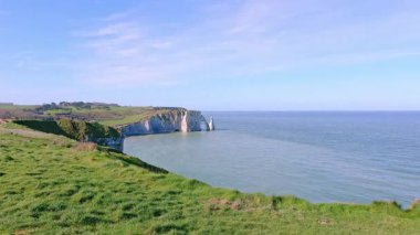 Dramatik beyaz tebeşir oluşumlarının altında ünlü Etretat uçurum kemeri ve turkuaz deniz manzarası yükseliyor. Normandiya kıyıları Fransa 'nın ikonik doğal simgesini temsil ediyor.