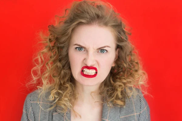 Screaming, hate, rage. Emotional woman is angry on red studio background. Emotional, young face, web banner. Expressive facial emotions