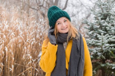 2021 'in modaya uygun rengi, parlak sarı ve nihai gri renkte sırıtan bir ceket, şapka ve eşarp giyen mutlu genç kadın.