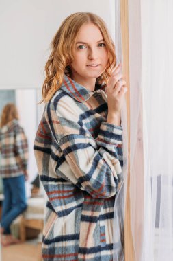 Gri duvar arkasında izole bir şekilde poz veren mutlu genç kadın görüntüsü. Yüz ifadesi, duygular ve tutum