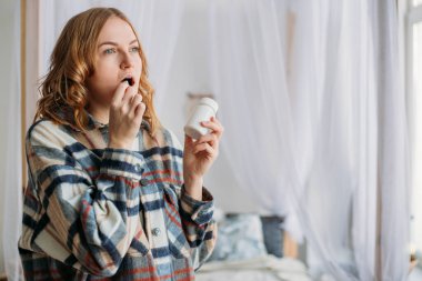 Sarışın kadının beyaz yuvarlak hapları ağzına koyduğu görüntüyü kapat. Hasta kadın ilaç, antidepresan, ağrı kesici ya da antibiyotik alıyor..