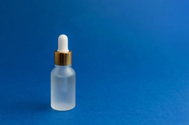 Mavi modaya uygun arka planda pipetli kozmetik şişesi. Bilim ya da tıbbi test konsepti.