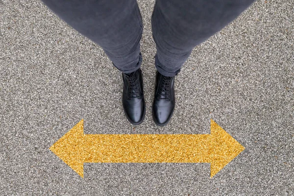 Черные туфли стоят на асфальтобетонном полу с желтым символом стрелки направления. Ноги обувь ходить на открытом воздухе. Молодой хипстер Selphie Modern — стоковое фото
