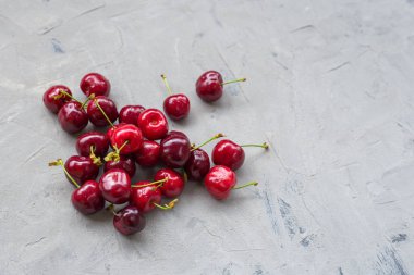 Gri taş masadaki su damlalarıyla dolu olgun bir kiraz. Üst Manzara. Kırsal tarzda. Yemek afişi, düz yatış. Grunge arka planında kiraz çileği