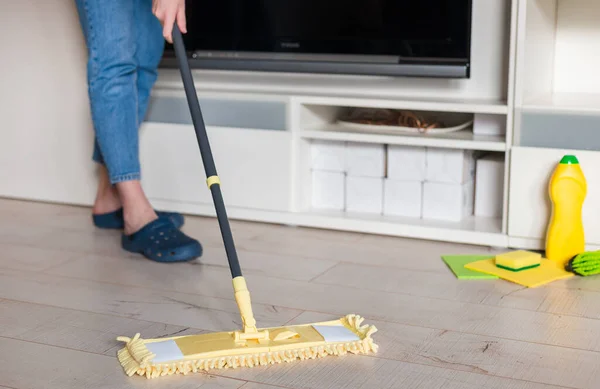Mujer limpiando piso con fregona amarilla en casa. Trapeador de microfibra aislado sobre fondo de madera blanca, primer plano, interior —  Fotos de Stock