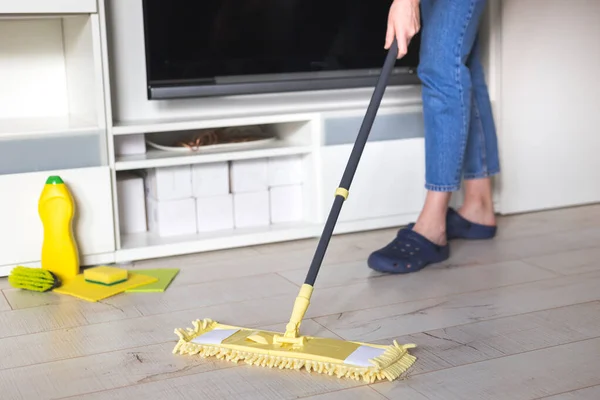 Mujer limpiando piso con fregona amarilla en casa. Trapeador de microfibra aislado sobre fondo de madera blanca, primer plano, interior — Foto de Stock