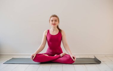 Genç ve sağlıklı bir kadın evde yoga yapıyor. Nilüfer çiçekli poz veriyor. Yoga minderinde dinleniyor. Kapalı alanda ve dışarıda egzersiz. Spor ve sağlıklı aktif yaşam tarzı konsepti.