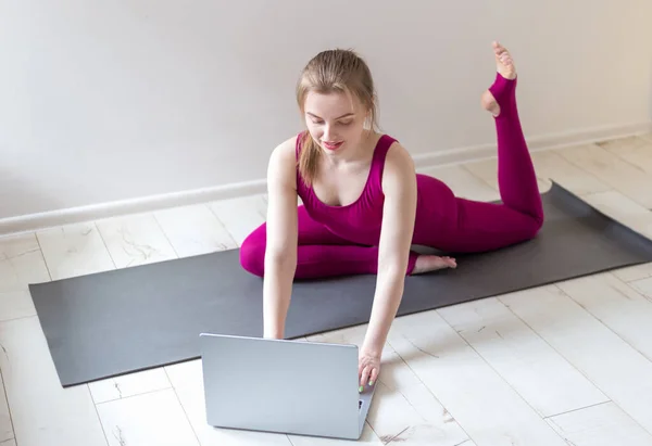 Молода щаслива фітнес-йога жінка працює зі своїм ноутбуком. Внутрішнє тренування. Спорт і здоровий спосіб життя концепція . — стокове фото