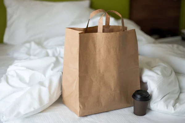 Lieferung Lebensmittel Craft Bag mit Tasse auf dem Bett an sonnigen Tag. Lieferung bei jedem Wetter rund um die Uhr an den Kunden. Fast Food Öko-Verpackung mit großem Frühstücksset — Stockfoto