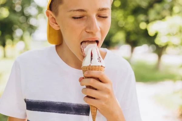 Niño adolescente comiendo cono de helado sobre fondo verde de la naturaleza. Verano, comida chatarra y concepto de personas —  Fotos de Stock