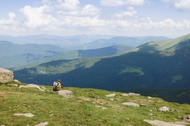 Dağlarda ağır sırt çantasıyla yürüyüş yapan aktif bir yürüyüşçü. Turizm ya da Özgürlük konsepti. Vahşi doğa, yaz manzarası. Toprağın güzelliğini keşfedin.