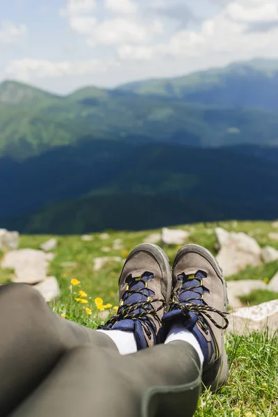 Traveler hiking boots on Beautiful mountain landscape view. Tourism or Freedom concept. Legs of traveler sitting making feet selfie on a high mountain in travel.