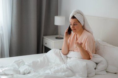 Kafkasyalı mutlu bir kadın evde rahat bir yatakta rahatlar ve cep telefonu kullanır, erkek arkadaşıyla konuşur. Dedikodu kavramı