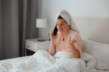 Kafkasyalı mutlu bir kadın evde rahat bir yatakta rahatlar ve cep telefonu kullanır, erkek arkadaşıyla konuşur. Dedikodu kavramı