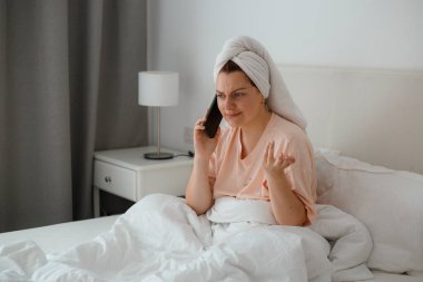 Kafkasyalı mutlu bir kadın evde rahat bir yatakta rahatlar ve cep telefonu kullanır, erkek arkadaşıyla konuşur. Dedikodu kavramı