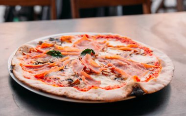 Prosciutto ve kırmızı soslu mantarlı fırında pizza ve siyah ahşap arka planda erimiş peynir. Yiyecek konsepti