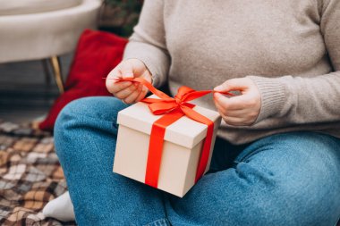 Mutlu Noeller, mutlu bayramlar. Mutlu, genç bir bayan Noel hediyeleri alıyor ve kanepenin yanında yere oturuyor ve Noel ağacını süslüyor..