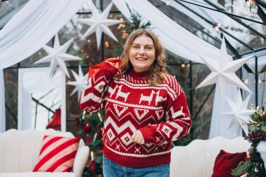 Orta yaşlı, beyaz bir kadın elinde Noel hediyesi çantası tutarak gülümsüyor. Kış ve tatiller. Kutlama bayrağı, büyük satış konsepti..