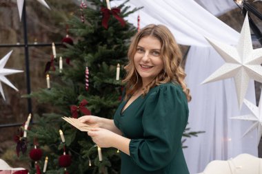 Genç bir kadın, Noel tebrik kartı alıyor. Arka planda, şenlikli iç mekanlı, rahat oturma odasındaki Xmas ağacından. Evde mektup okumaktan hoşlanan bir kadın için sürpriz oldu..