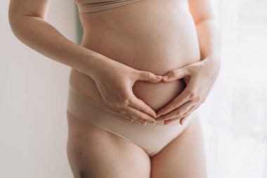 Güzel bir hamile göbeğine yakın çekim. Hamile bir kadın karnına dokunup bebeğine dokunuyor ve sağlığını önemsiyor. Annelik kavramı.