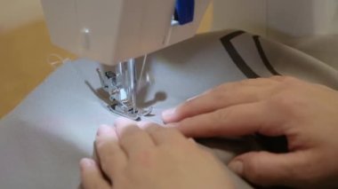 the process of working as a seamstress on a sewing machine. close-up, slow motion. hands of a seamstress in the process of sewing.