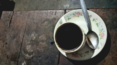 Zengin, sade bir kahvenin yüksek açılı görüntüsünü bir kaşıkla sunan klasik bir seramik fincanda güzel dokulu, ahşap bir yüzey üzerinde dinlenen huzurlu bir an için mükemmel..