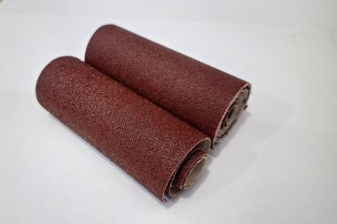 Alüminyum oksit zımpara kağıdı yüzey zımparalama ve cilalama için aşındırıcı kağıt sarar. Profesyonel ahşap işçiliği ekipmanları DIY konut yenileme projeleri için beyaz arka planda izole.