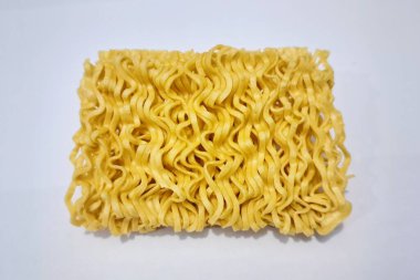 Anında kurutulmuş erişte bloğu beyaz arka planda izole edilmiş yüksek açılı, hızlı yemek hazırlama ve fast food konsepti için sarı dalgalı erişteyi yakın çekim..