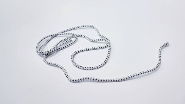 Bu detaylı görüntü, beyaz bir yüzey üzerinde doğal olarak sarmalanmış benekli siyah-beyaz bir araç halatı içeriyor. Tekstil ve dikiş tasarım projeleri için mükemmel..