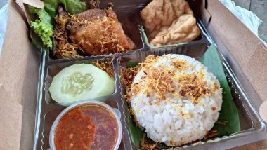 İçinde kızarmış tavuk, sambal ve tofu bulunan tam bir Endonezya pirinç kutusu. Yerel yemek servisleri ve geleneksel yemek menüleri için ideal..