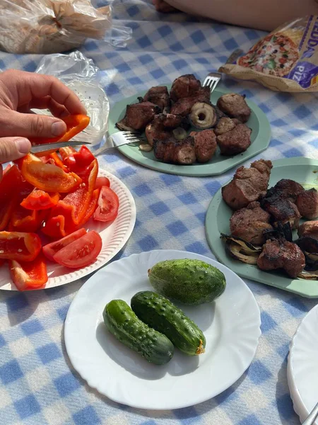 Tabaklarda taze sebzeler ve ızgara et sergileniyor, kırmızı biber elde yetişiyor, lezzetle dolu davetkar bir açık hava yemek atmosferi yaratıyor.