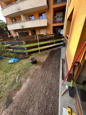 Yeni dönüştürülmüş toprak, ahşap çit ve bahçe aletleri, çevre düzenlemesi ve ev iyileştirme faaliyetleri ile inşaat halindeki açık bahçe yolu