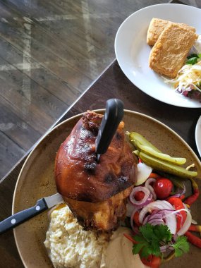 Köy tabağında sunulan kızarmış et tabağına kremalı patates püresi, taze sebze ve turşu eşlik ediyor. Lezzetli mutfak sanatları sergileniyor.