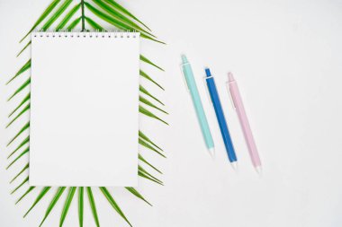 Beyaz arkaplanda kalemler olan beyaz not defteri