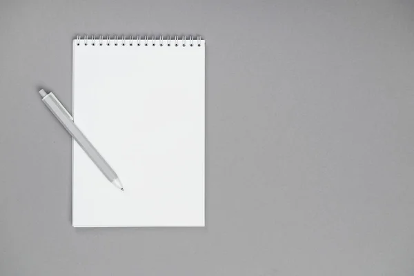 Um bloco de notas com lápis e rascunhos em um fundo cinza — Fotografia de Stock