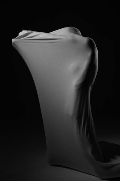 a girl posing in fabric on a black background