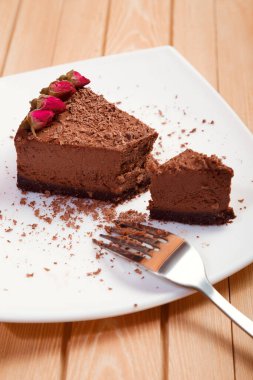 Tahta arka planda beyaz bir tabakta bir parça çikolatalı pasta.