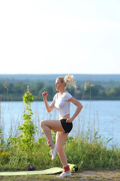 Fiatal gyönyörű nő fut azt mutatja, hogy nyomja meg a gyomor edzés képzés rajta tetején. — Stock Fotó