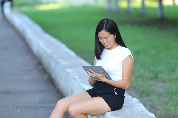 Mladá dívka v parku učení s počítačem tablet — Stock fotografie