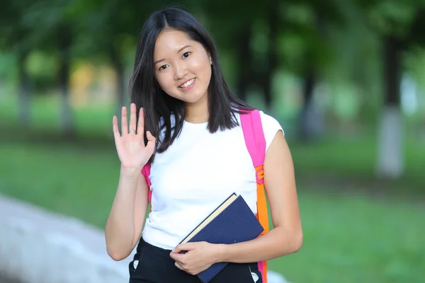 Young girl go in the park walking looking at the camera and waves — Stock Fotó