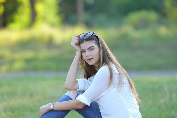 Jonge meisje zit in het park, glimlachend en werkt op zijn laptop. — Stockfoto