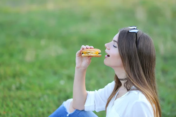 Girl on the nature of eating fast food — Stock Photo, Image