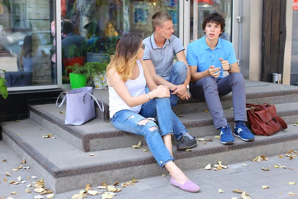 Junge drei Freunde sitzen Boden auf der Straße, reden, verwenden — Stockfoto