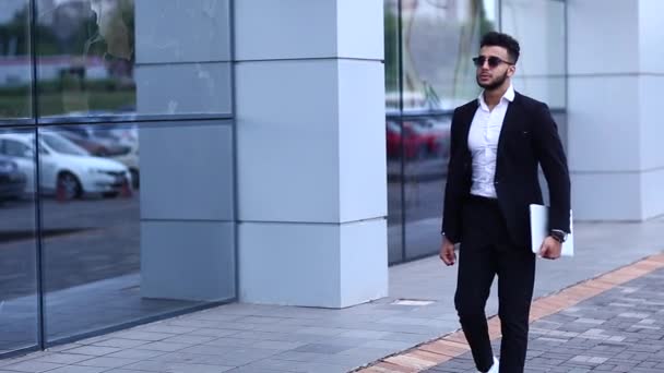 Арабский парень в бизнес-центре стоит улыбаясь ходьба медленно — стоковое видео