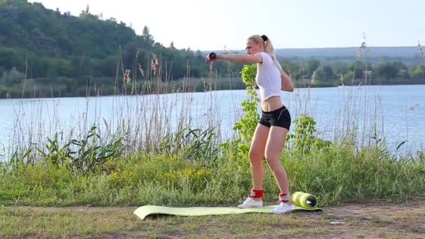 Vrouwelijke atleet squats gewogen arm benen training outdors — Stockvideo