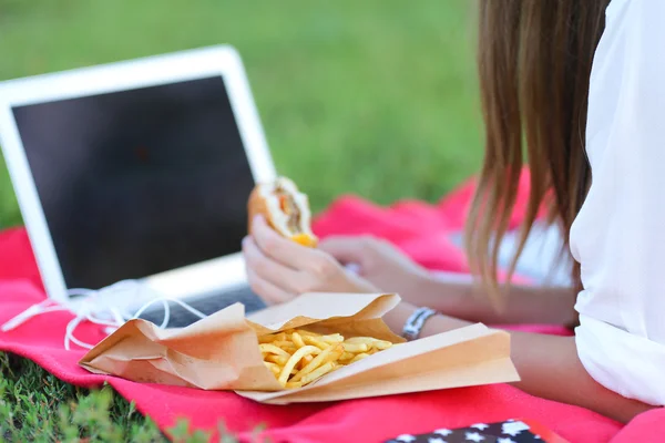 Молодая девушка о природе быстрого питания и работы на ноутбуке — стоковое фото