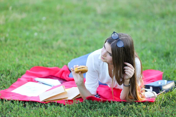 Lavoro femminile sdraiato in bicchieri nel parco e spuntino alimentare — Foto Stock