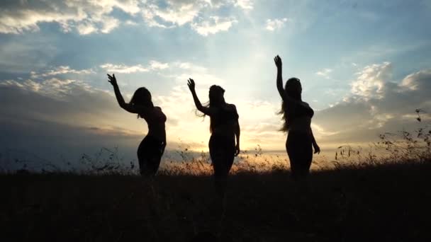 Sziluettjét három lány jóga háttér napnyugtakor ég felhők — Stock videók